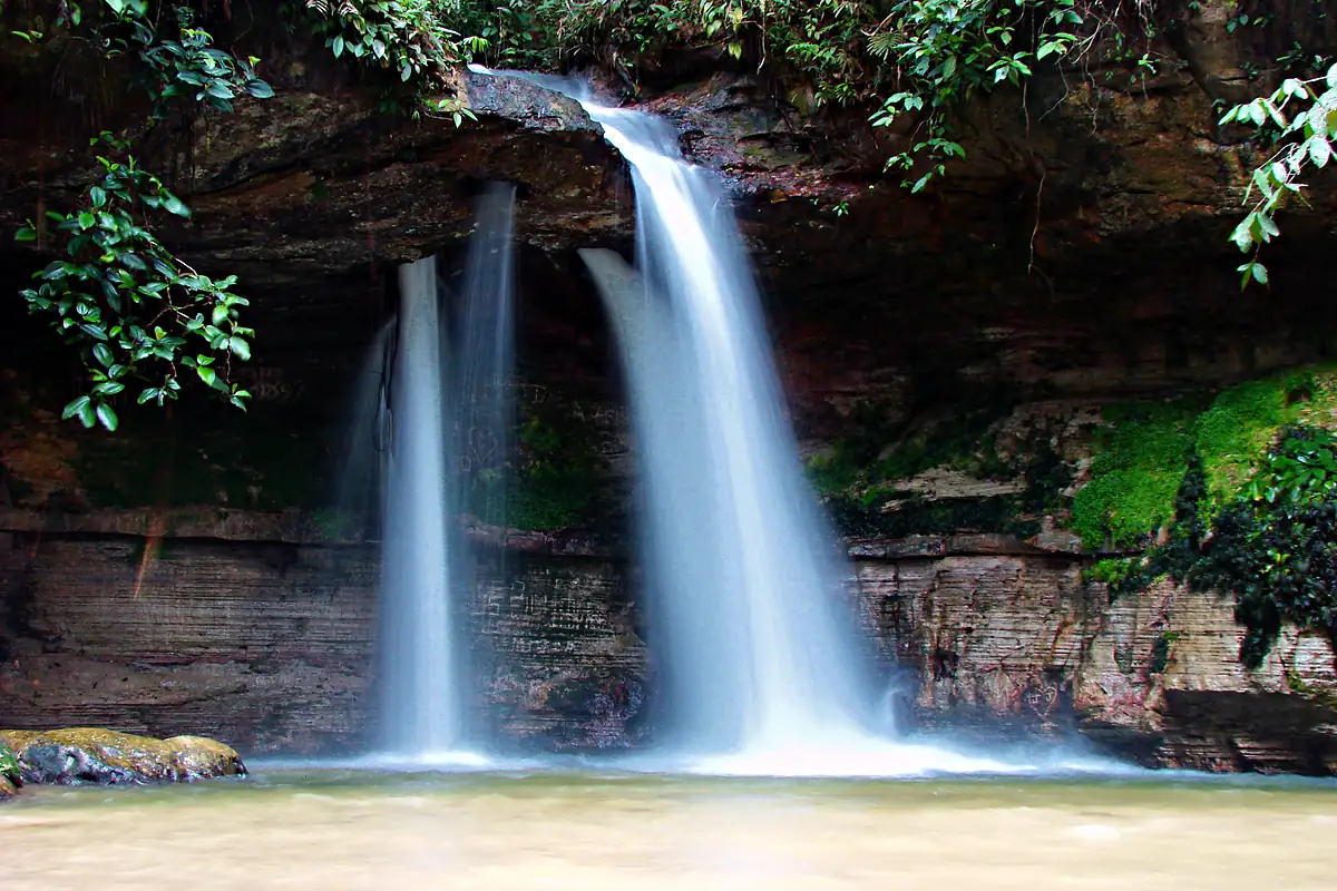 Cachoeira da Pedra Furada, em Presidente Figueiredo, com duas quedas caindo de um paredão de pedra coberto de mata