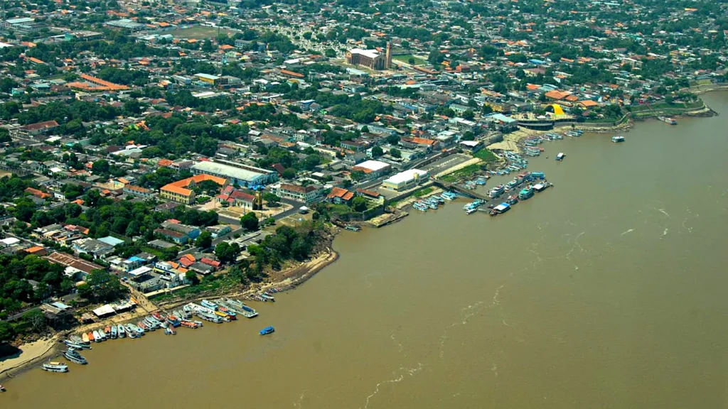 Vista aérea da orla de Parintins com barcos atracados no porto às margens do rio Amazonas de água barrenta e a cidade ao fundo