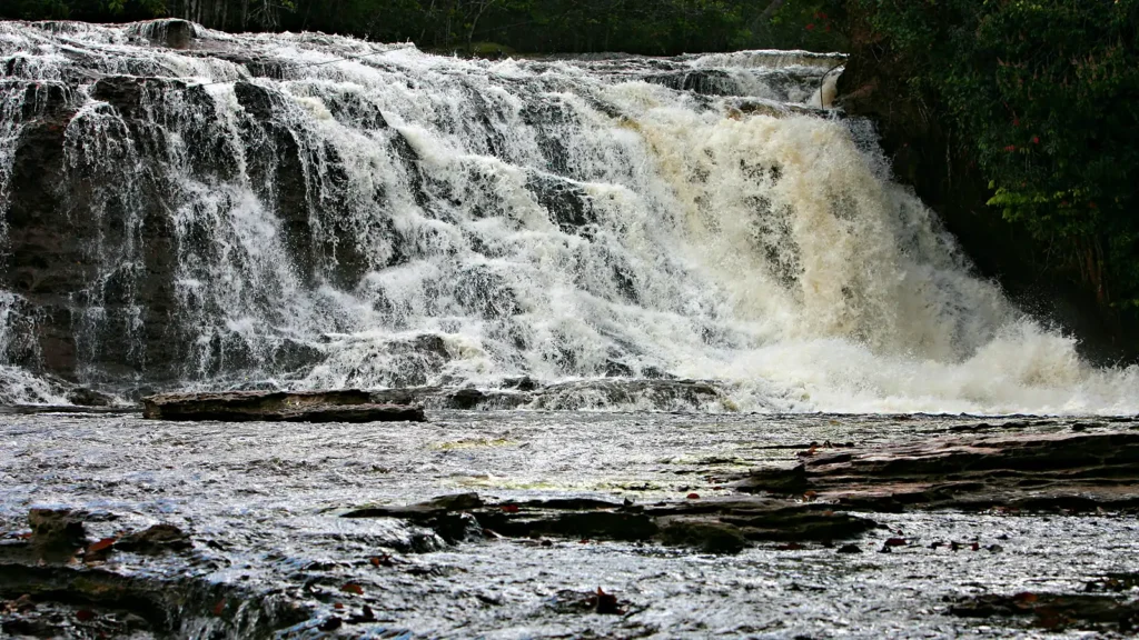 Cachoeira de Iracema, em Presidente Figueiredo, com a água caindo em degraus de pedra escura e a mata fechada nas margens