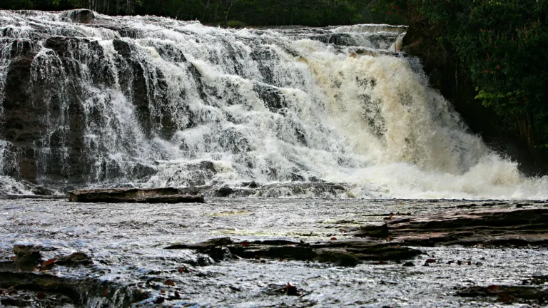 Cachoeira de Iracema, em Presidente Figueiredo, com a água caindo em degraus de pedra escura e a mata fechada nas margens