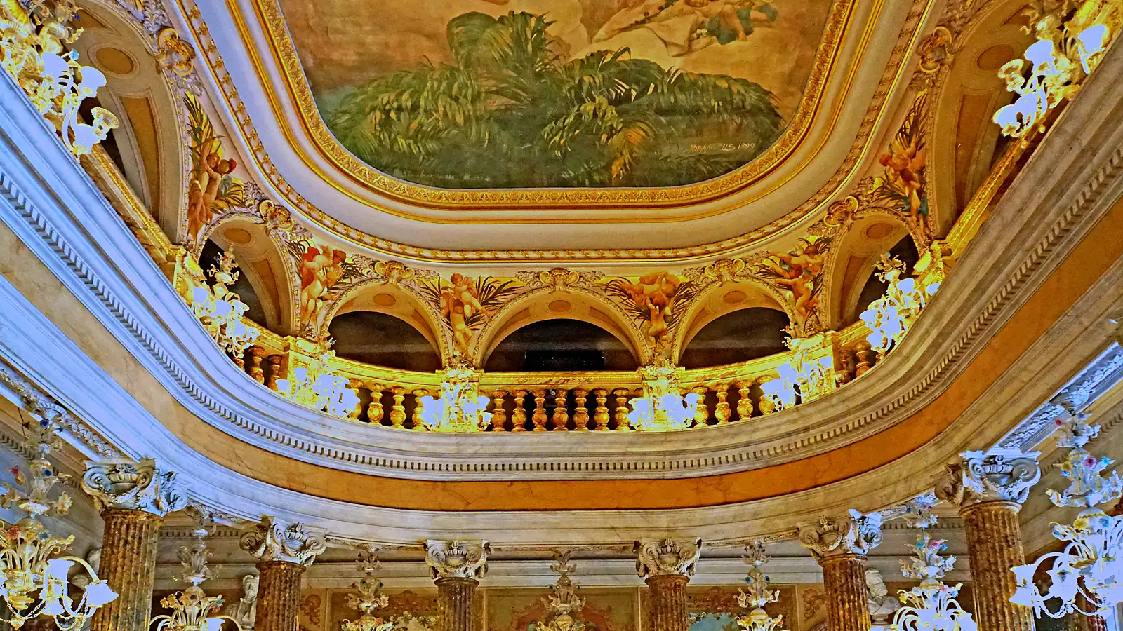 Teto do Salão Nobre do Teatro Amazonas, com a pintura de Domenico de Angelis cercada de moldura dourada, anjos pintados nos arcos, galeria de balaústres dourados, colunas de mármore e lustres de vidro